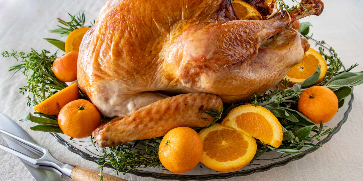 Golden roasted Thanksgiving turkey garnished with fresh herbs, orange slices, and tangerines, perfect for a festive holiday feast.