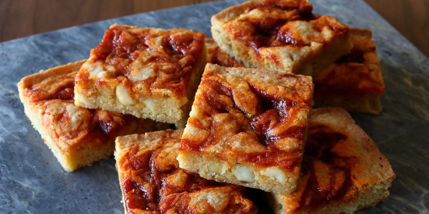 Halloween blondies with a golden-brown texture, swirled with spicy gochujang caramel and macadamia nuts, perfect for festive celebrations.